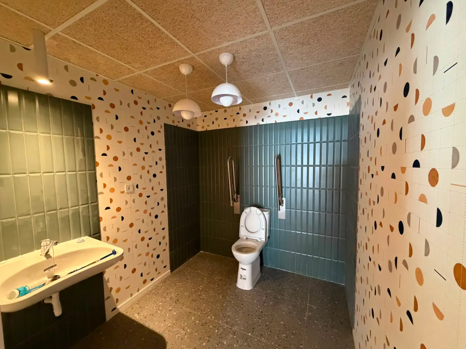 Reforma de baño adaptado con azulejos geométricos de colores y barras de apoyo en Madrid