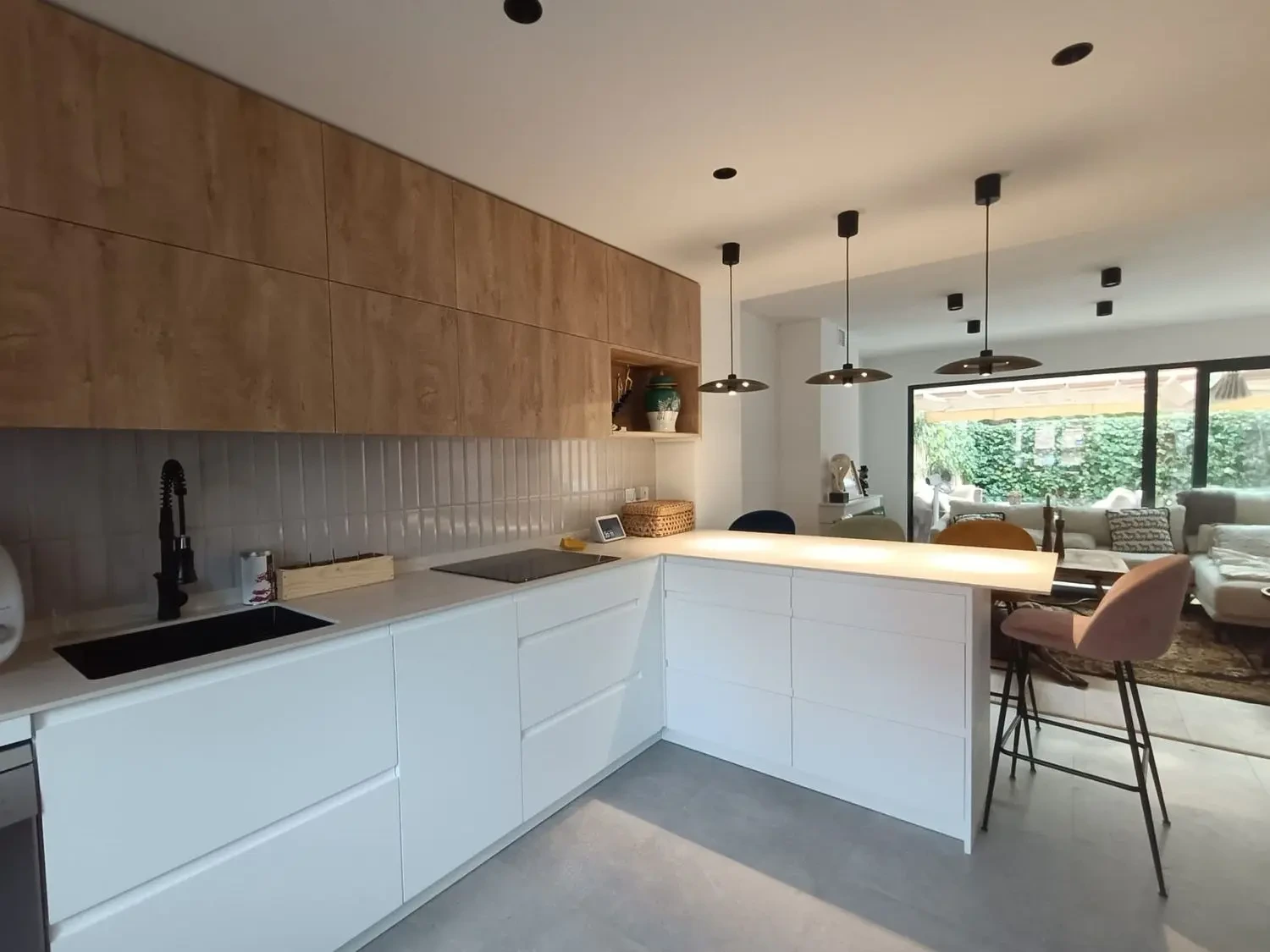 Reforma de cocina con armarios de madera, península blanca y grifería negra en Madrid