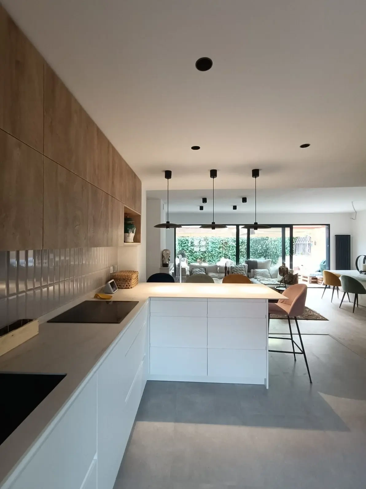 Reforma cocina con península blanca, armarios superiores de madera y suelo gris en Madrid