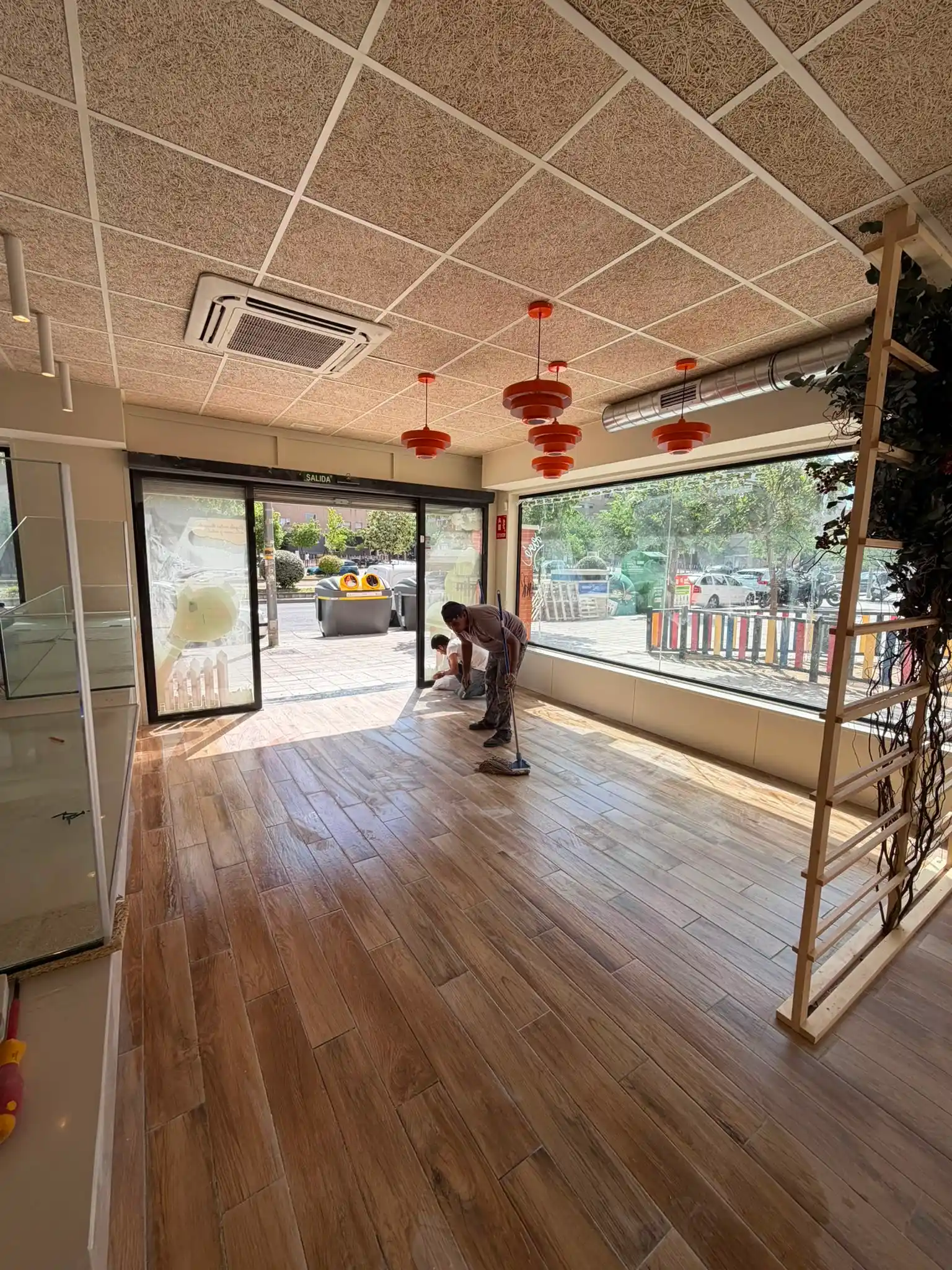 Reforma integral de local con operario instalando suelo cerámico de imitación madera en Madrid