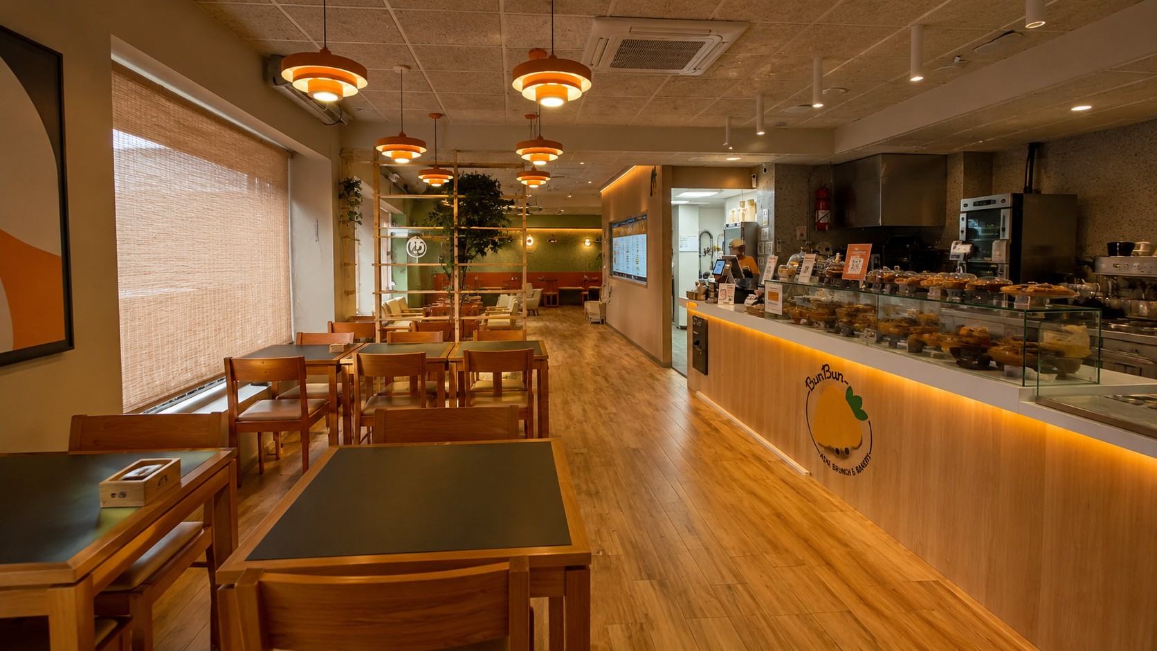Reforma integral de local comercial con suelo laminado de madera y luminarias naranjas en Madrid