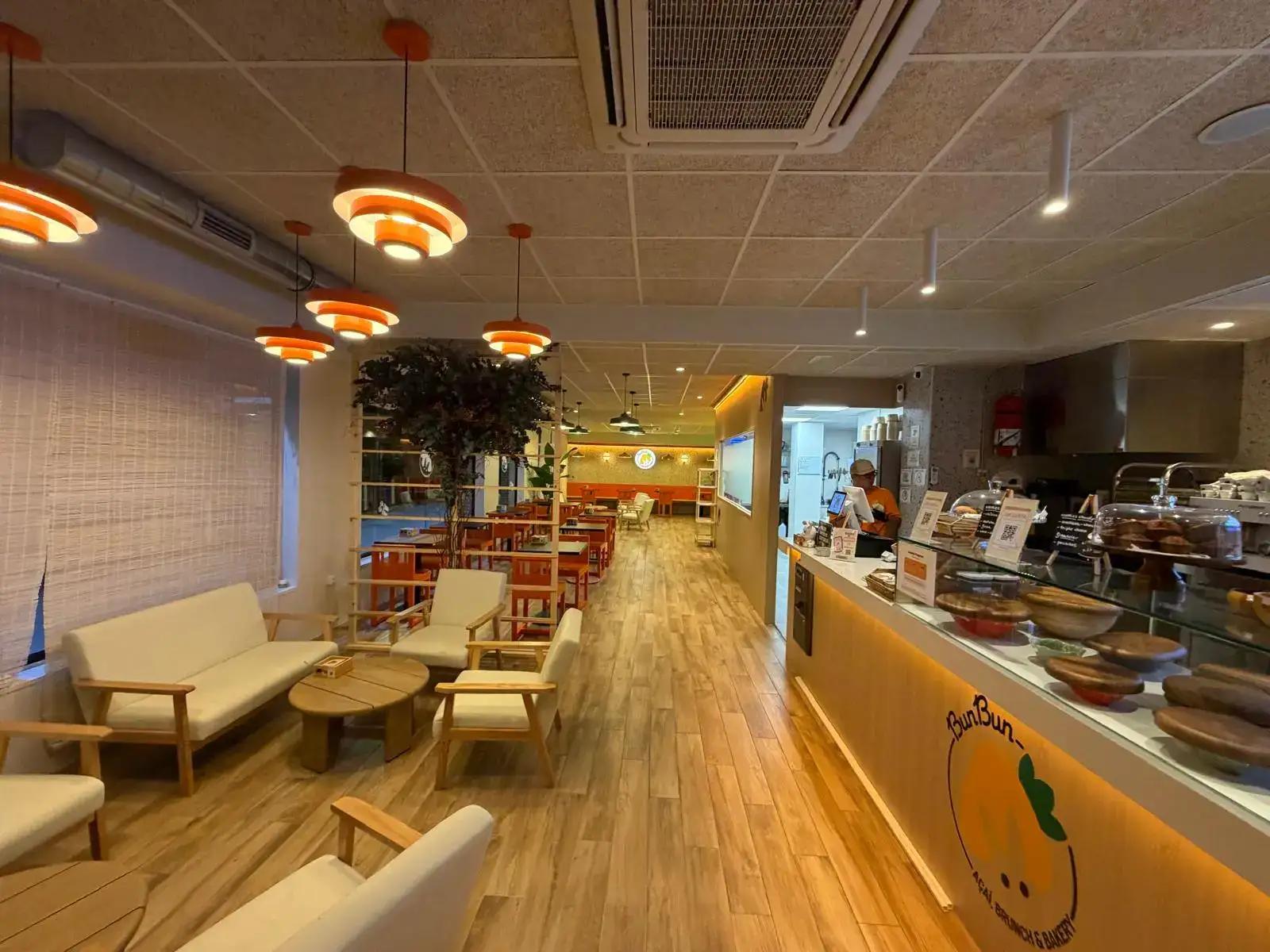 Reforma integral de local comercial con suelo laminado de madera y luminarias naranjas en Madrid